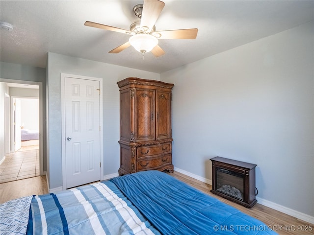 bedroom featuring light wood-style flooring, baseboards, and ceiling fan