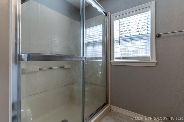 full bath with tile patterned floors, baseboards, and a shower with shower door