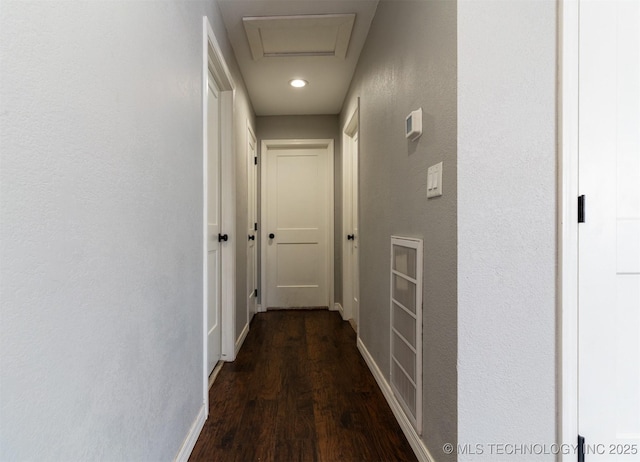 hall with dark wood-style floors, attic access, and baseboards