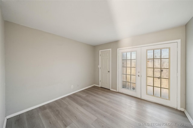 empty room featuring french doors, wood finished floors, and baseboards