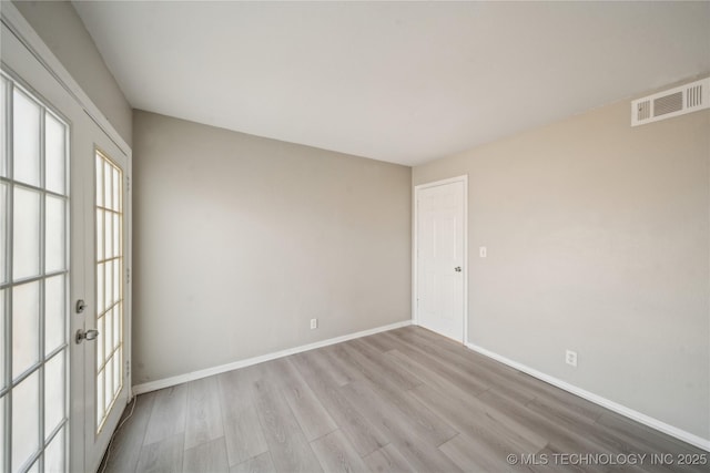 spare room featuring wood finished floors, visible vents, and baseboards