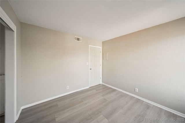 unfurnished room with visible vents, baseboards, and wood finished floors