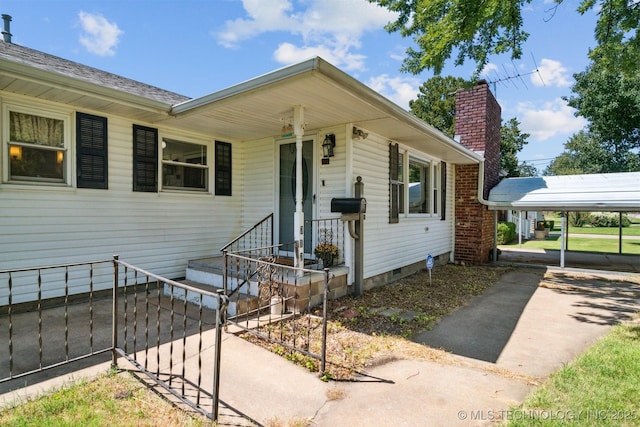 view of front of house featuring a carport, crawl space, a chimney, and driveway