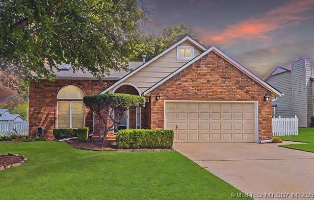 view of front of home with brick siding, concrete driveway, an attached garage, a front yard, and fence