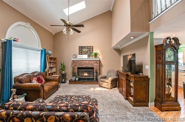 living area featuring a skylight, ceiling fan, a brick fireplace, and ornamental molding