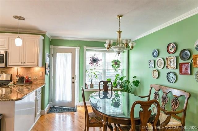 dining room featuring baseboards, an inviting chandelier, light wood-style flooring, and crown molding