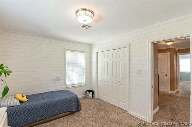 carpeted bedroom featuring baseboards, a closet, visible vents, and crown molding