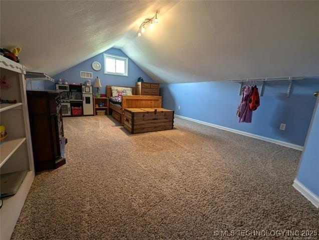 bedroom with lofted ceiling, carpet, and baseboards