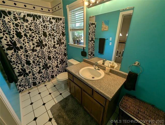 full bathroom featuring curtained shower, vanity, and toilet