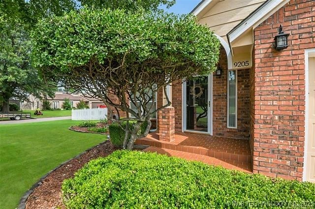 entrance to property with a lawn and brick siding