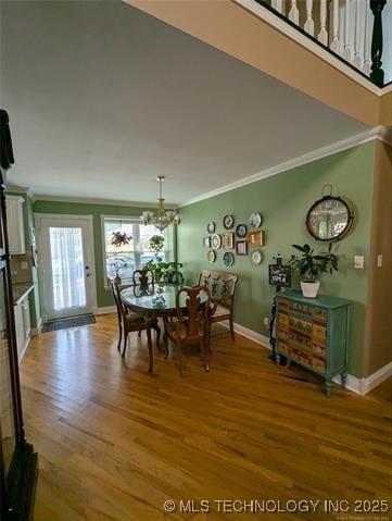 dining room featuring ornamental molding, an inviting chandelier, wood finished floors, and baseboards