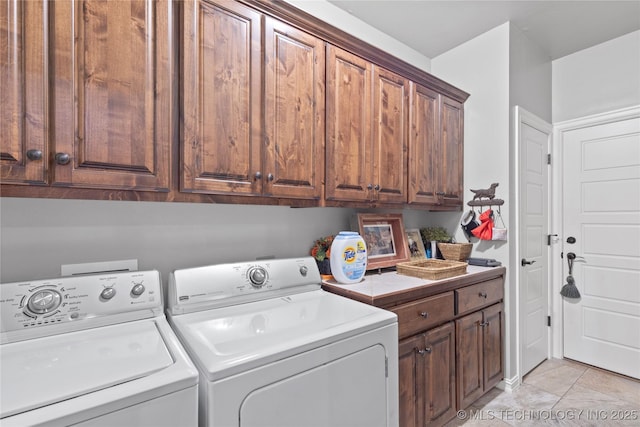 laundry area with cabinet space, independent washer and dryer, and light tile patterned floors