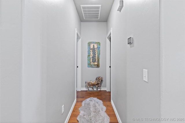 hall featuring visible vents, baseboards, and wood finished floors