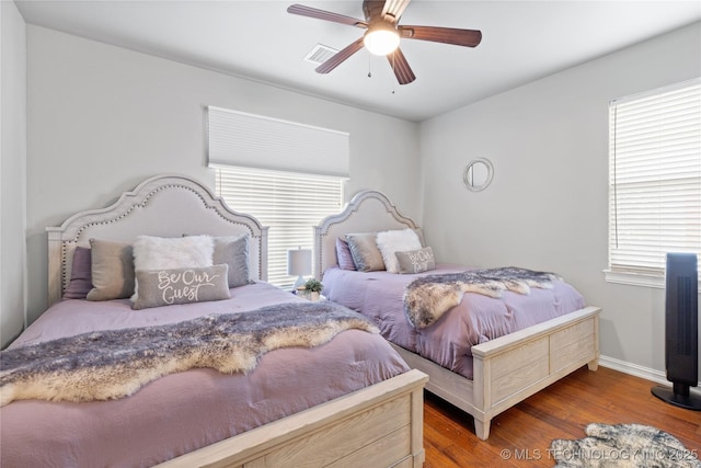 bedroom featuring a ceiling fan, baseboards, visible vents, and wood finished floors