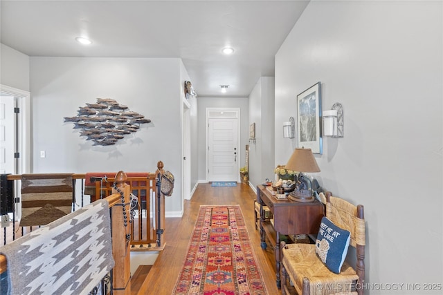 hallway with recessed lighting, baseboards, an upstairs landing, and wood finished floors