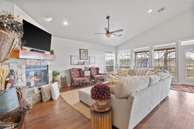 living area featuring lofted ceiling, a fireplace, visible vents, and wood finished floors