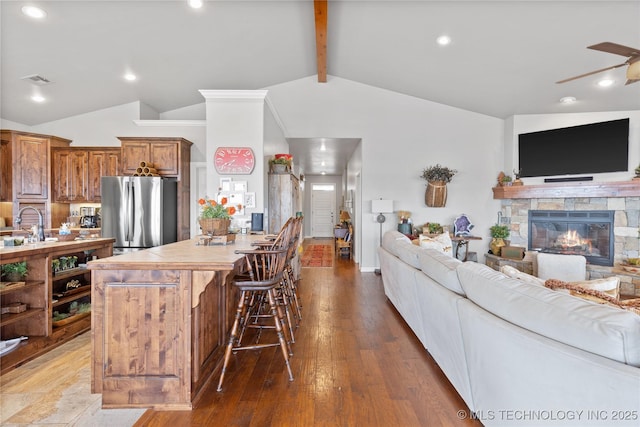 kitchen featuring vaulted ceiling with beams, open floor plan, tile counters, freestanding refrigerator, and brown cabinetry