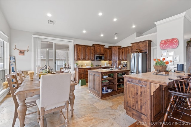 kitchen with a center island with sink, visible vents, tile counters, stainless steel appliances, and open shelves