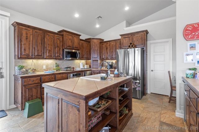 kitchen with tasteful backsplash, tile countertops, lofted ceiling, stainless steel appliances, and a sink