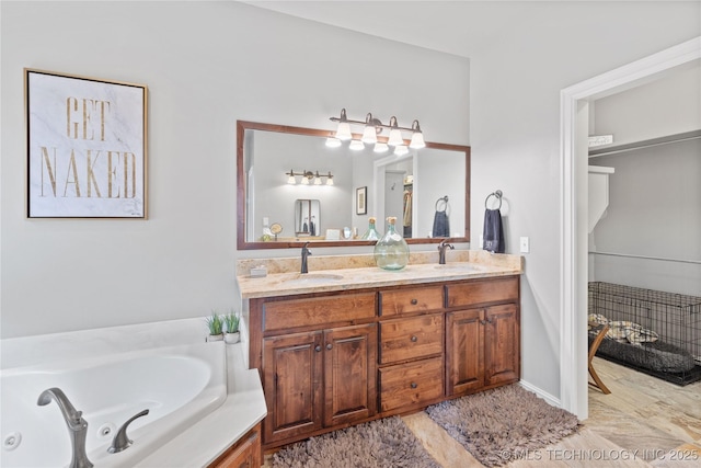 bathroom featuring a sink, a jetted tub, and double vanity