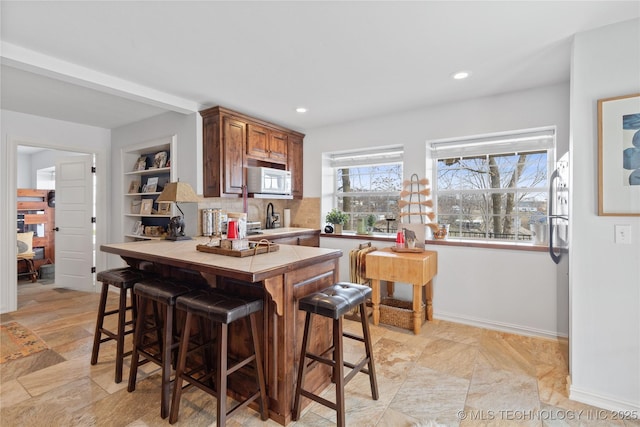 kitchen featuring tile countertops, baseboards, a breakfast bar area, and recessed lighting