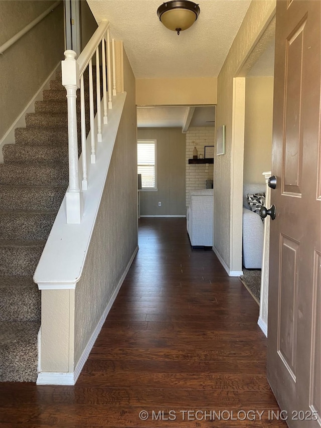 corridor featuring stairway, dark wood finished floors, a textured ceiling, and baseboards