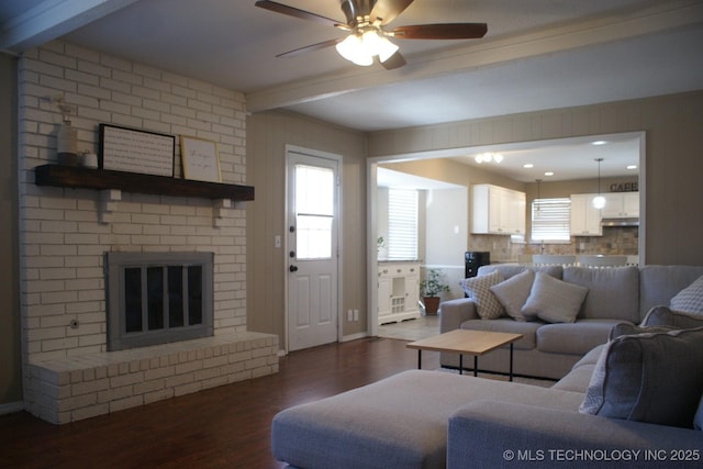 living room with dark wood-type flooring, a wealth of natural light, beam ceiling, and a fireplace