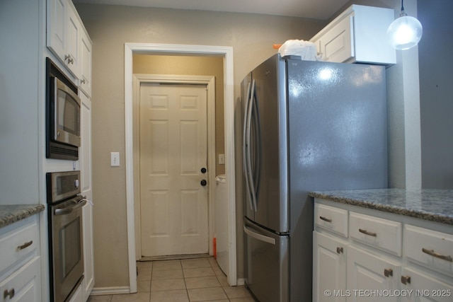 kitchen featuring appliances with stainless steel finishes, stone counters, white cabinetry, and light tile patterned floors