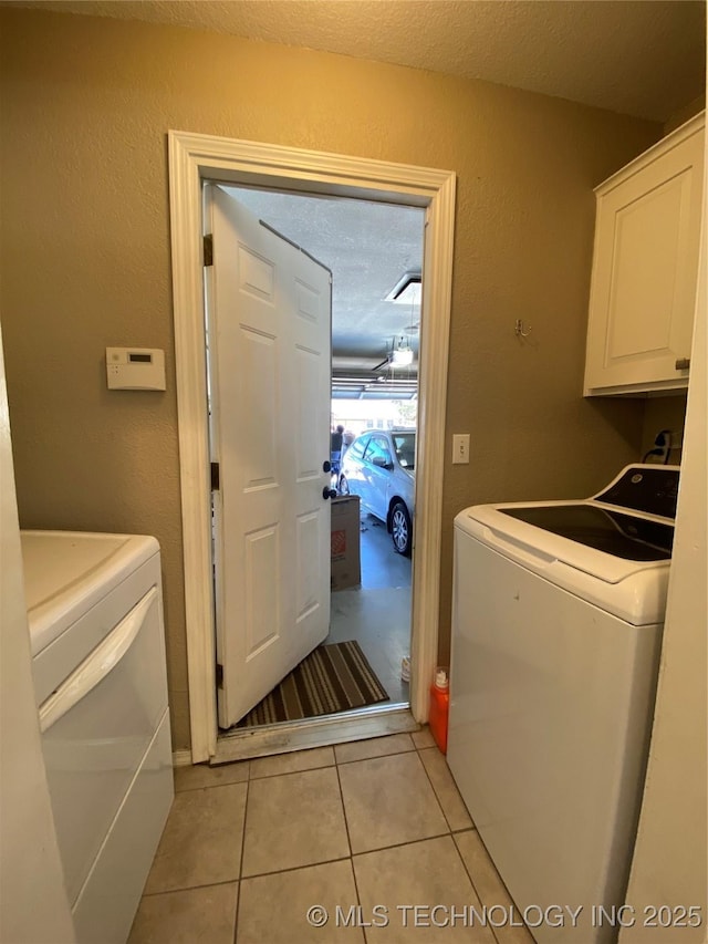 laundry area featuring cabinet space, light tile patterned floors, a textured ceiling, and independent washer and dryer