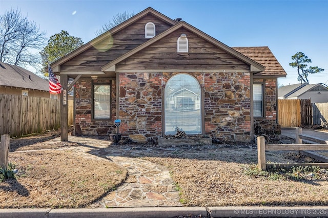 view of front of house with stone siding and fence