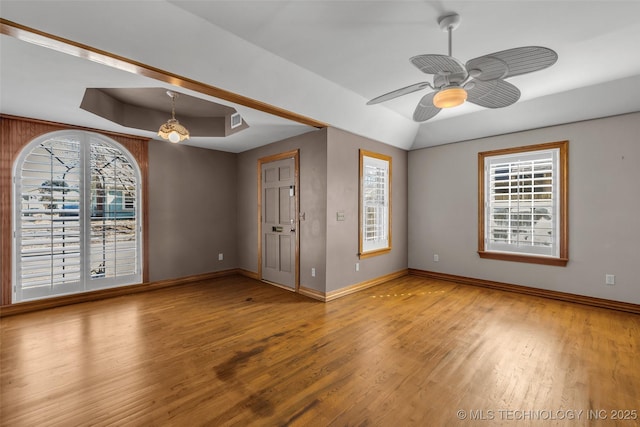 spare room with a tray ceiling, a healthy amount of sunlight, and wood finished floors