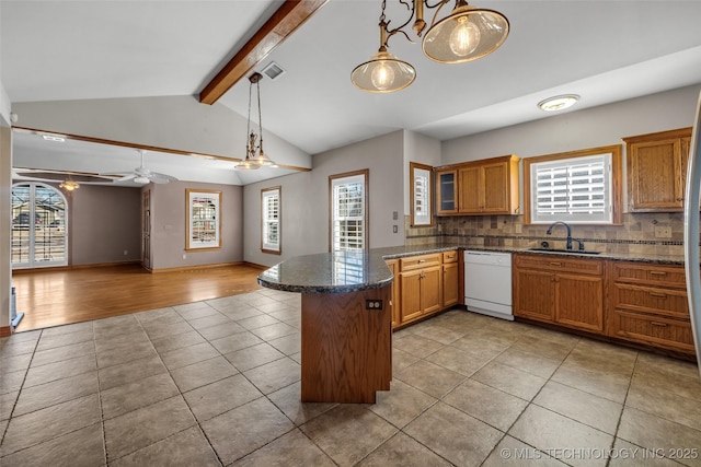 kitchen featuring brown cabinetry, a peninsula, a sink, white dishwasher, and a wealth of natural light