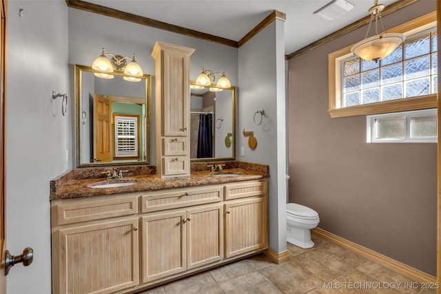 bathroom featuring crown molding, baseboards, a sink, and toilet