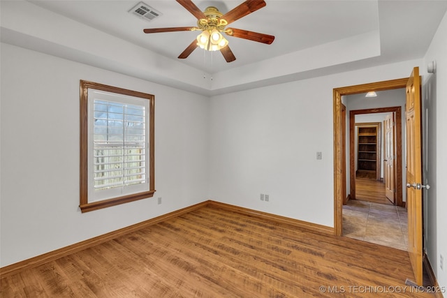 unfurnished room with visible vents, a raised ceiling, and wood finished floors