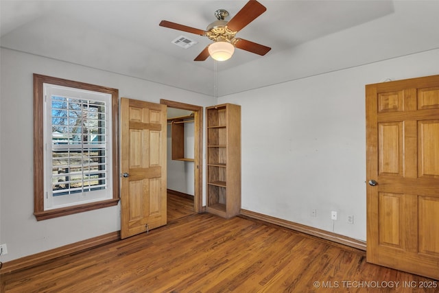 unfurnished bedroom featuring visible vents, ceiling fan, baseboards, and wood finished floors