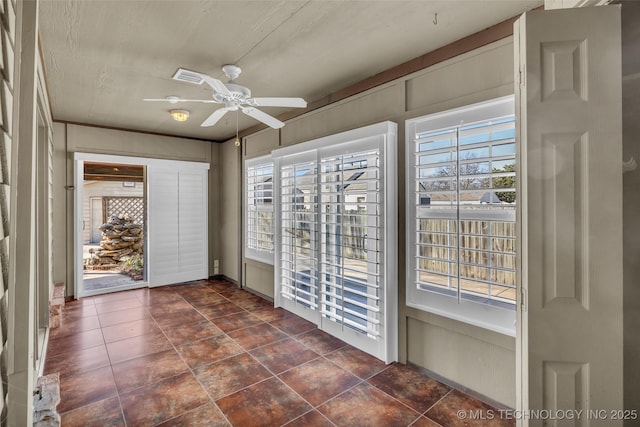 unfurnished sunroom with visible vents and a ceiling fan