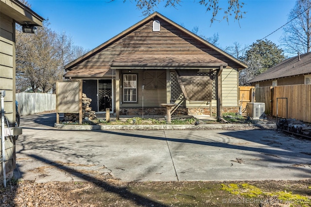 view of front facade featuring stone siding, a shingled roof, and fence