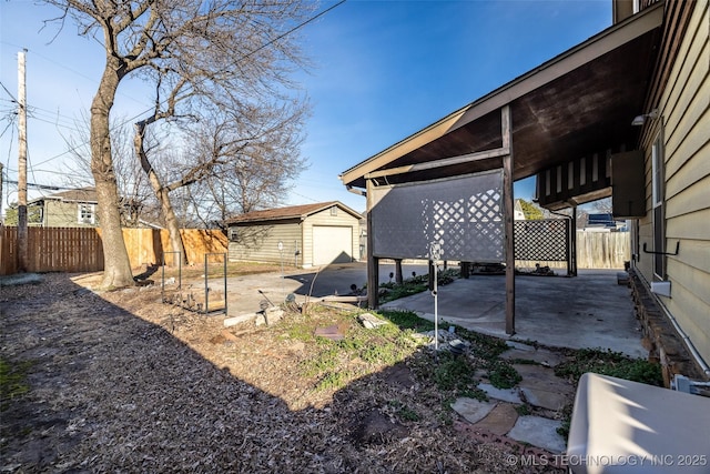 view of yard with a garage, an outbuilding, fence, and driveway