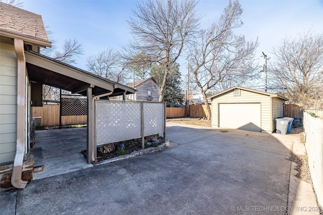 view of yard with an outbuilding, concrete driveway, a detached garage, and fence