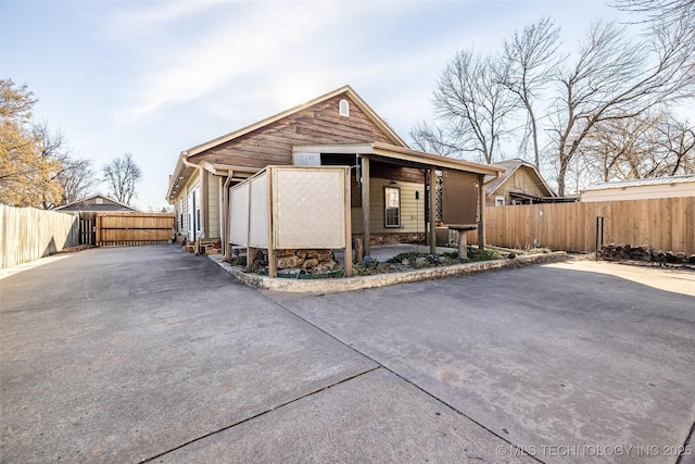 view of front of home with driveway, stone siding, and fence