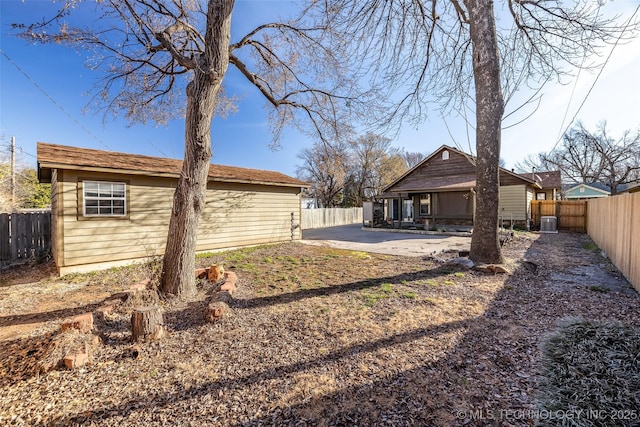 back of property with an outbuilding, a patio area, a fenced backyard, and central air condition unit