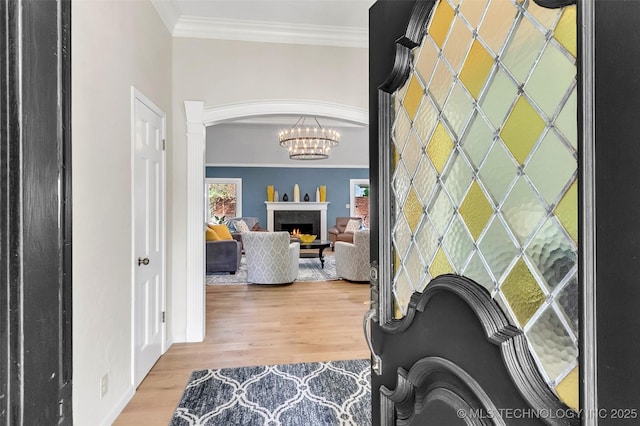 interior space featuring ornamental molding, a chandelier, a healthy amount of sunlight, and light wood-style flooring