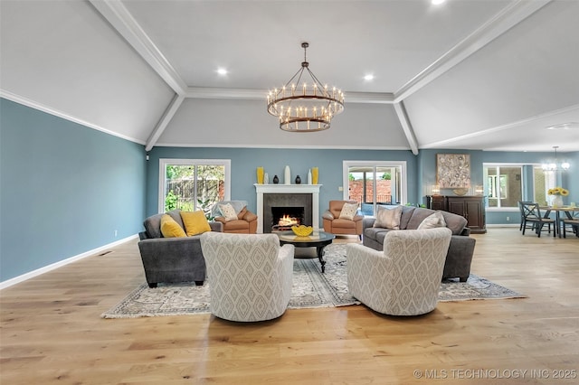 living area with a healthy amount of sunlight, a warm lit fireplace, crown molding, and a notable chandelier