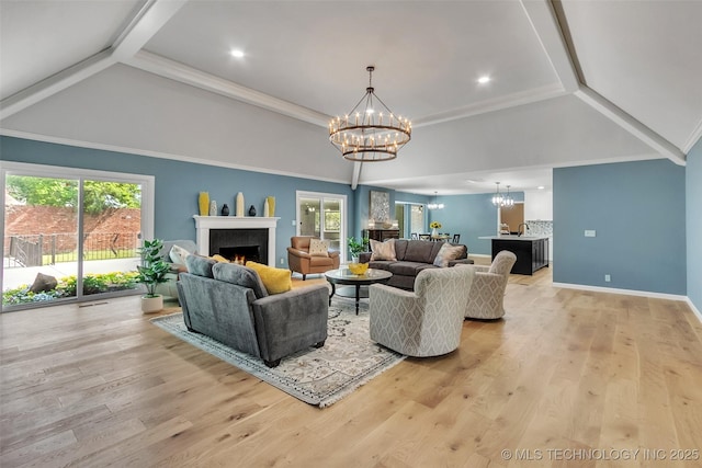 living area with light wood-style floors, a warm lit fireplace, ornamental molding, and an inviting chandelier