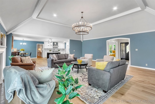 living area with arched walkways, a notable chandelier, light wood-style floors, vaulted ceiling, and crown molding