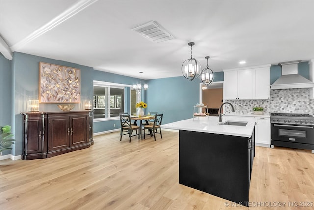 kitchen featuring visible vents, high end stainless steel range oven, custom exhaust hood, light countertops, and a sink