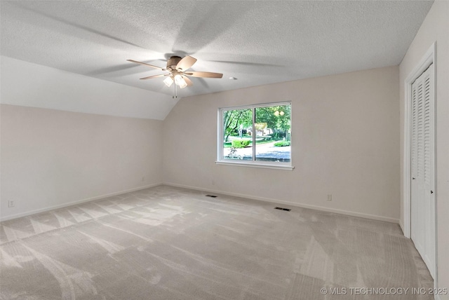 unfurnished bedroom featuring lofted ceiling, light carpet, visible vents, baseboards, and a closet