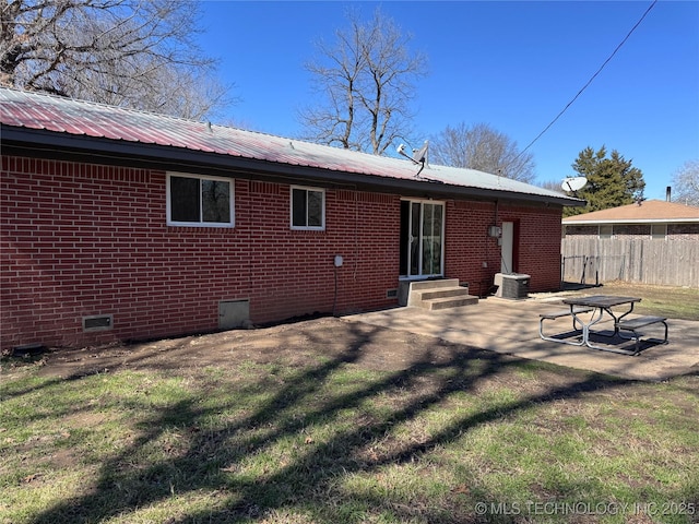 rear view of property featuring crawl space, fence, metal roof, and brick siding