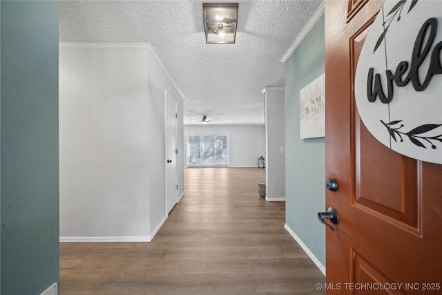 corridor featuring crown molding, wood finished floors, baseboards, and a textured ceiling