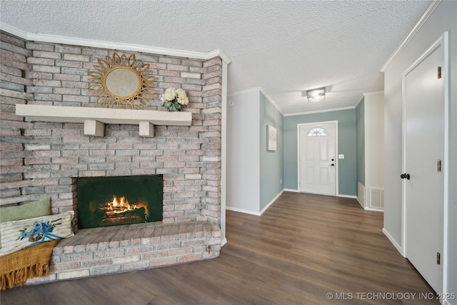 entrance foyer with visible vents, a textured ceiling, wood finished floors, crown molding, and a brick fireplace